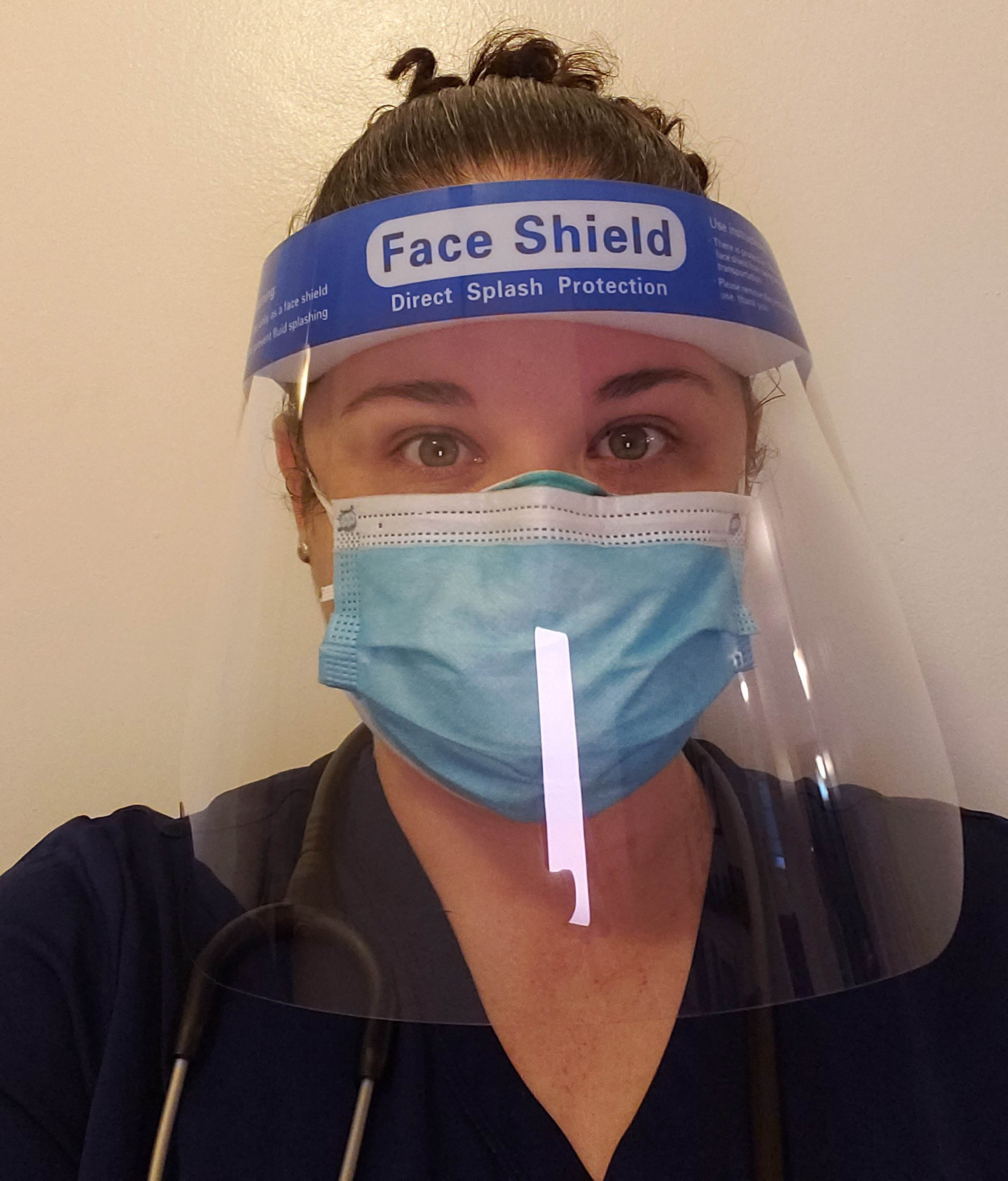 A nurse is seeing wearing a face shield and mask