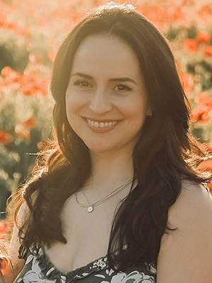 A woman standing in a field of red-colored flowers.