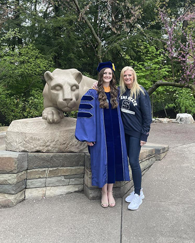 Two women pose in front of the Nittany Lion Shrine.