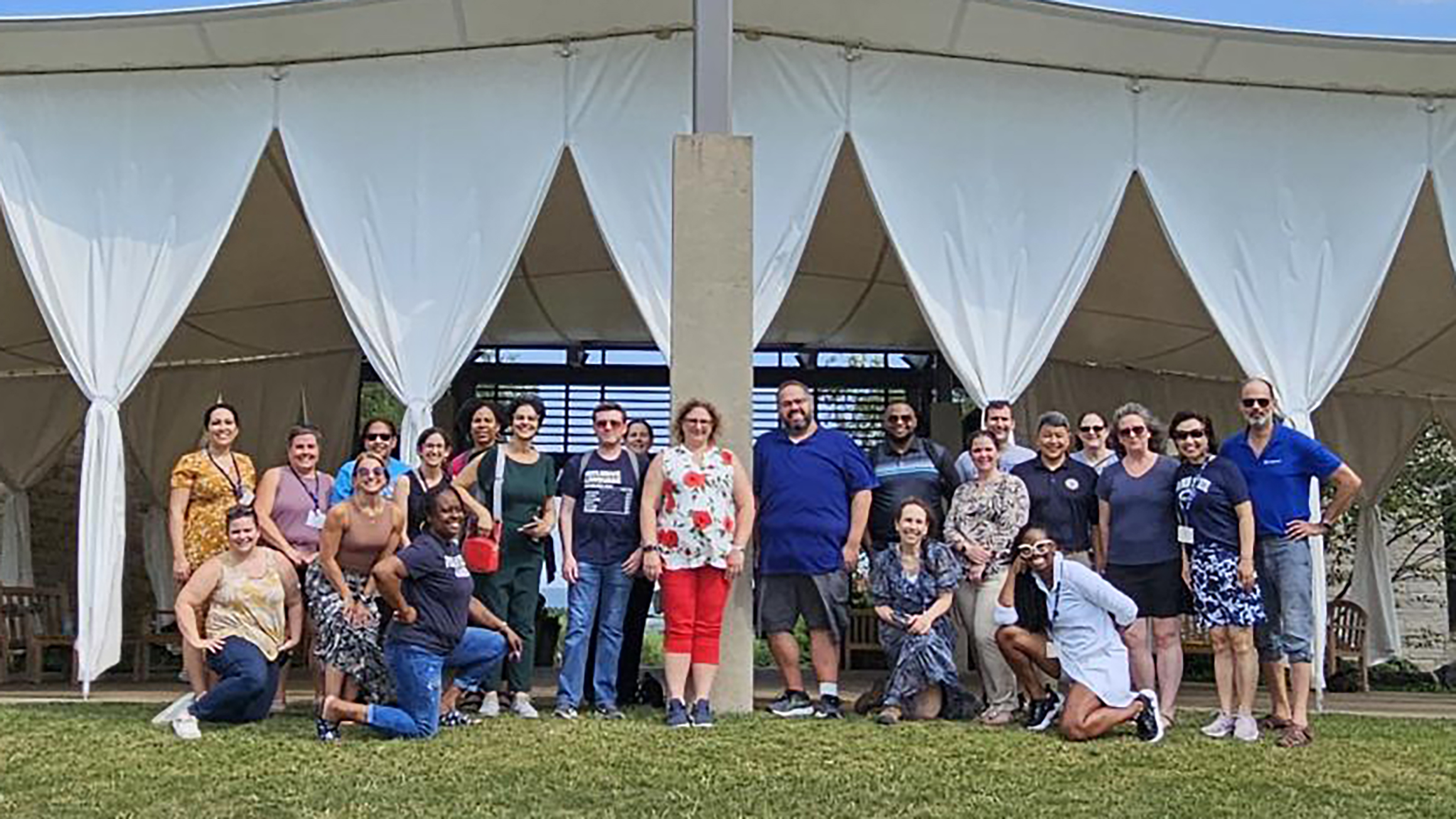 A group of people stand in front of a white outdoor tent.