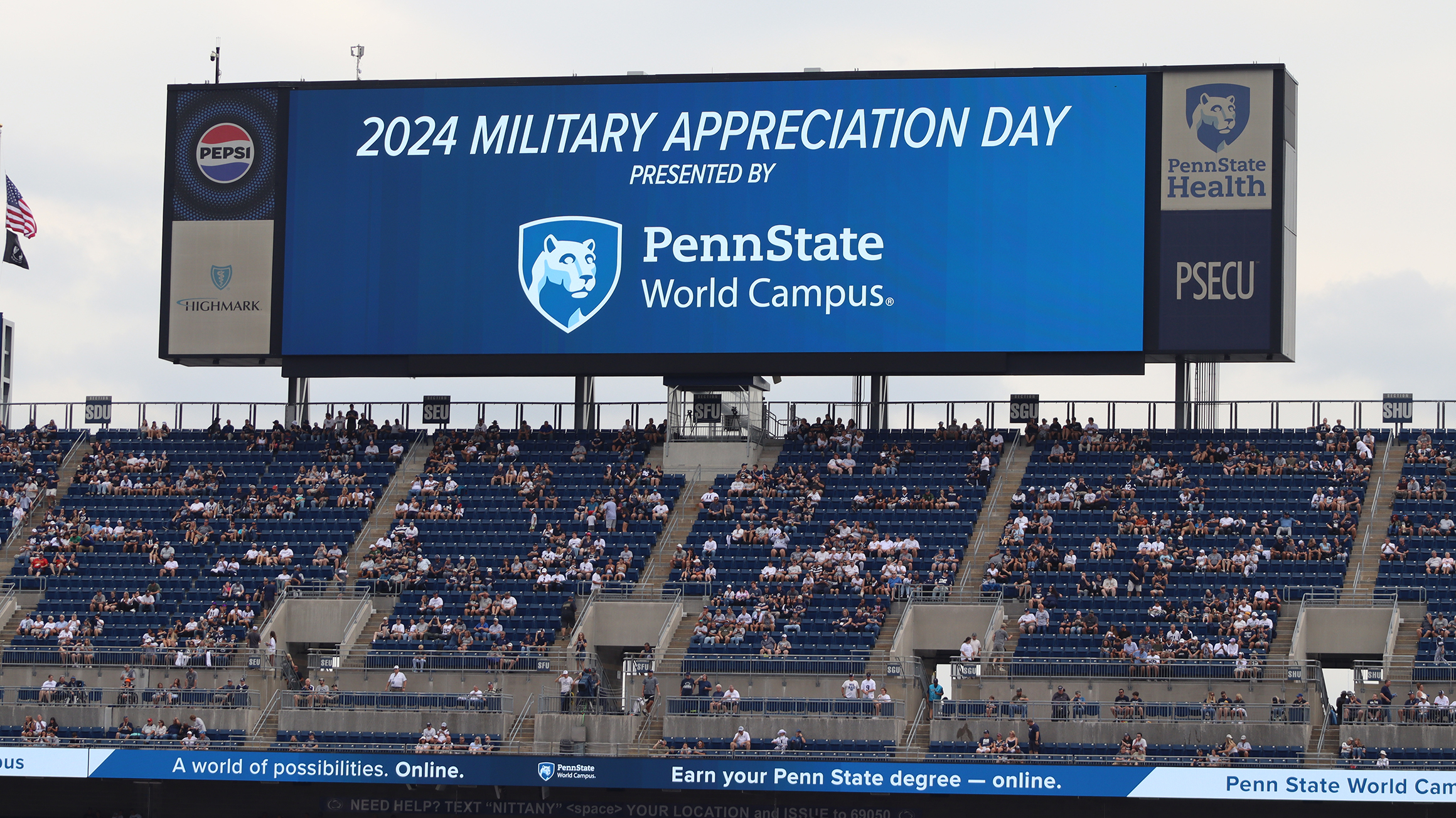 An electronic screen in a stadium with a Penn State World Campus logo.