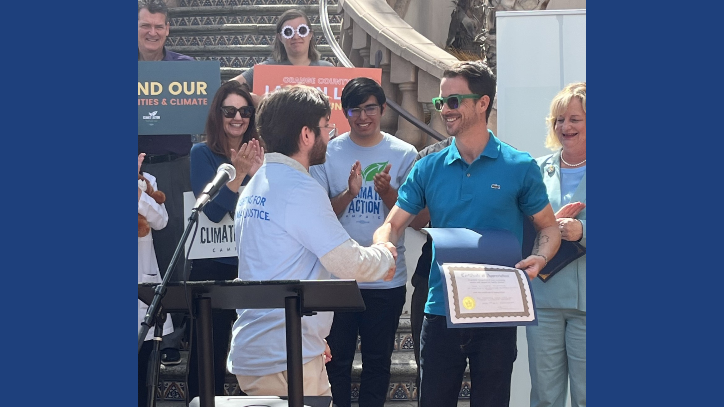 A man shakes another man's hand while holding a certificate.