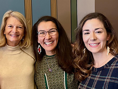 Three women pose together to take a selfie.