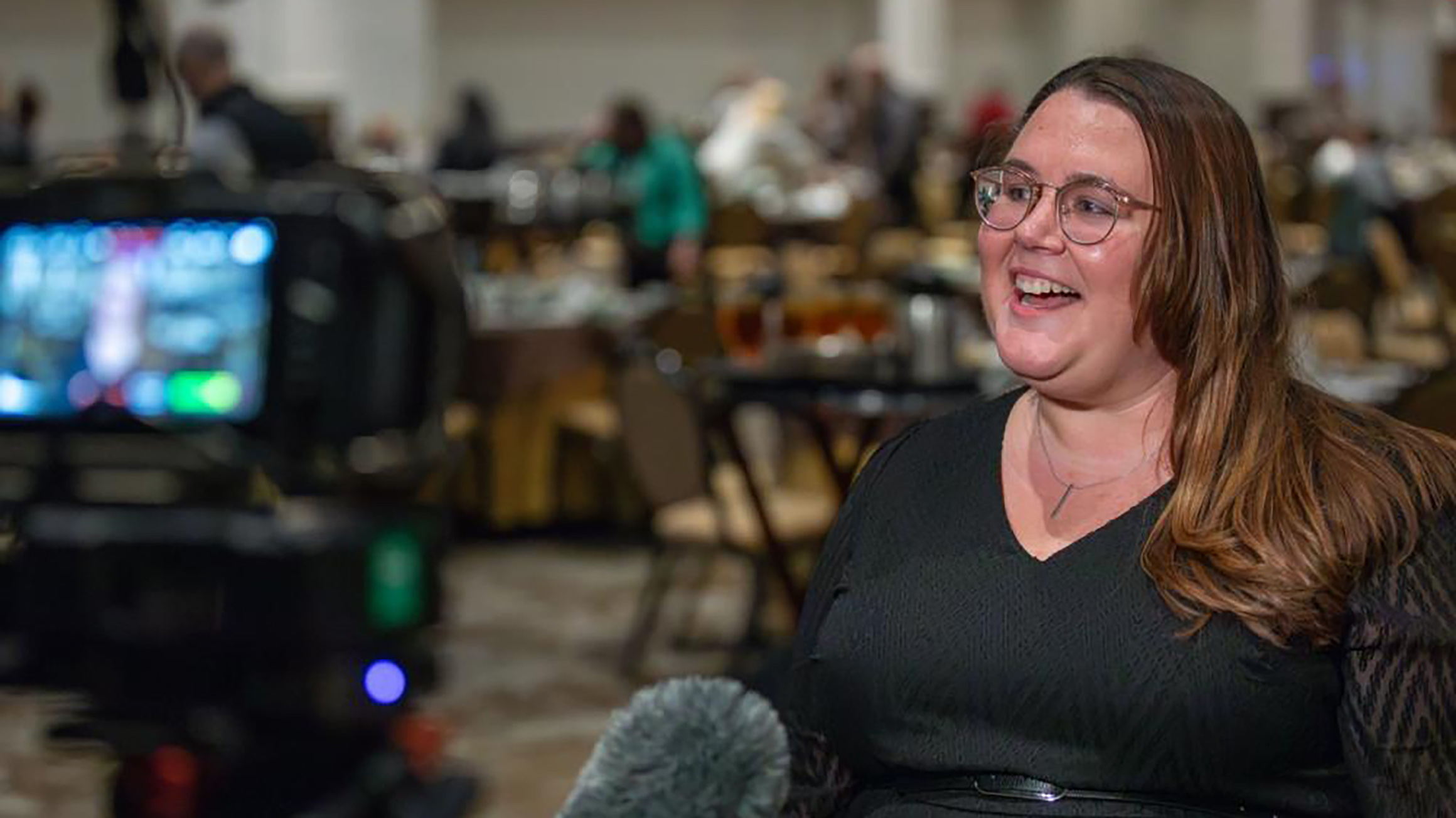  A woman is interviewed by a TV reporter in a conference room.