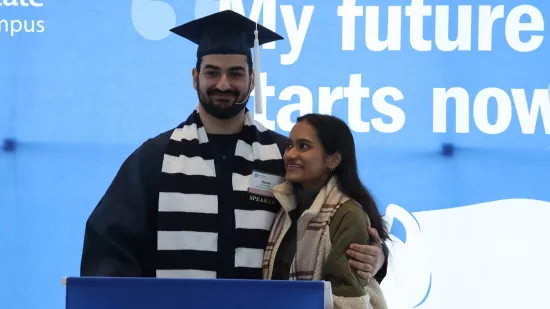 Derek Bagga stands at a podium with his girlfriend