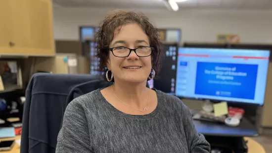 Tracey McCloskey at her desk, with a computer screen behind her