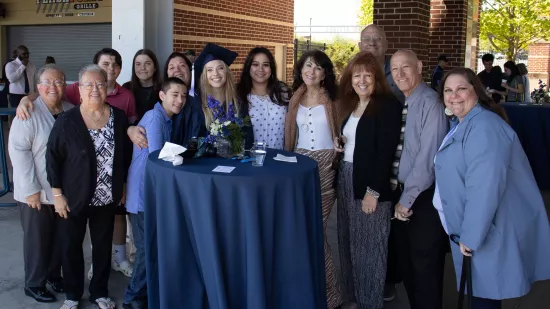 A group poses together around a graduate for a photo.