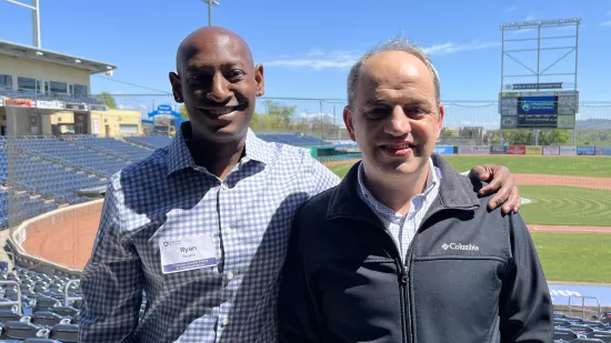 Ryan Boykin poses with his professor, Ahmet Guler, with a baseball field in the background.