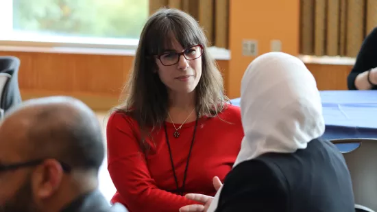 Two women seated at a table have a conversation.