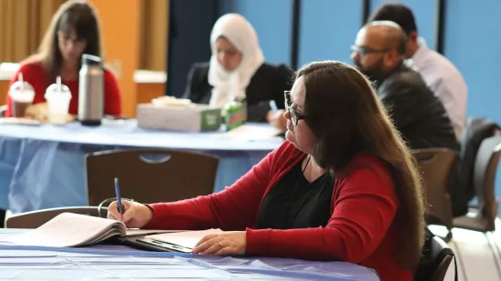 A woman take notes while sitting at a table.