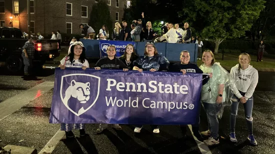 A group of people pose with a banner in front of a wagon.