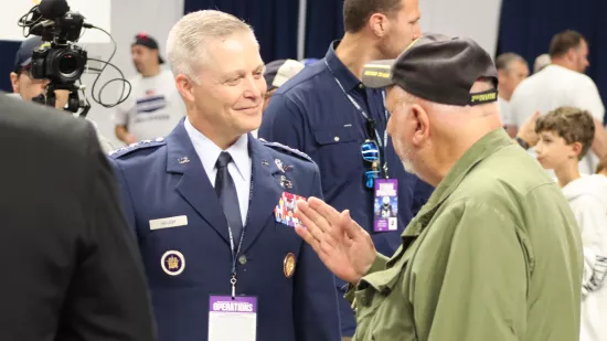 A man wearing a military uniform having a conversation with another man.