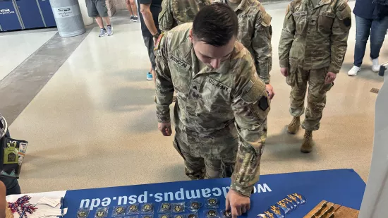 A man wearing a military uniform picks up a coin from a table.