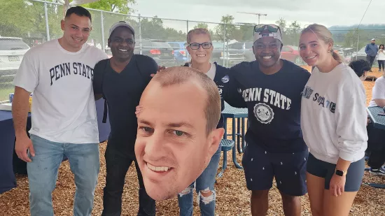 A group of people pose with a large cutout of Devon Love's face.