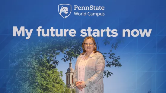 A woman stands in front of a Penn State-themed backdrop.