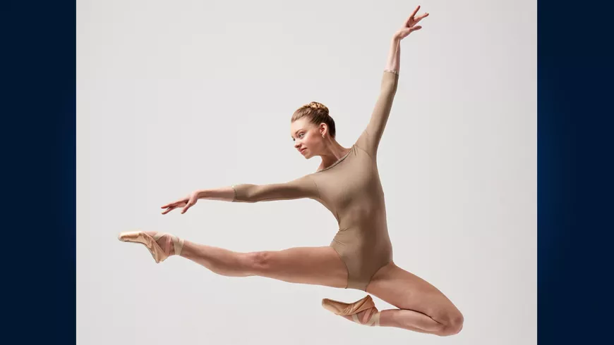 A ballerina leaping in front of a white background.